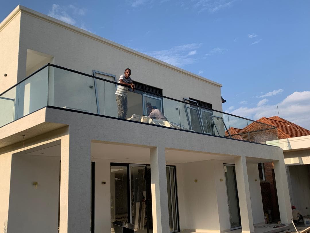 Glass balcony railings and aluminum-framed sliding doors on a modern white residence