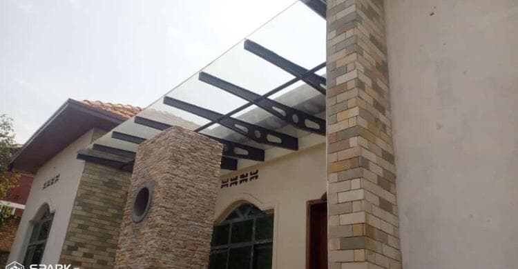 Glass canopy with custom aluminum support beams on a residential entrance