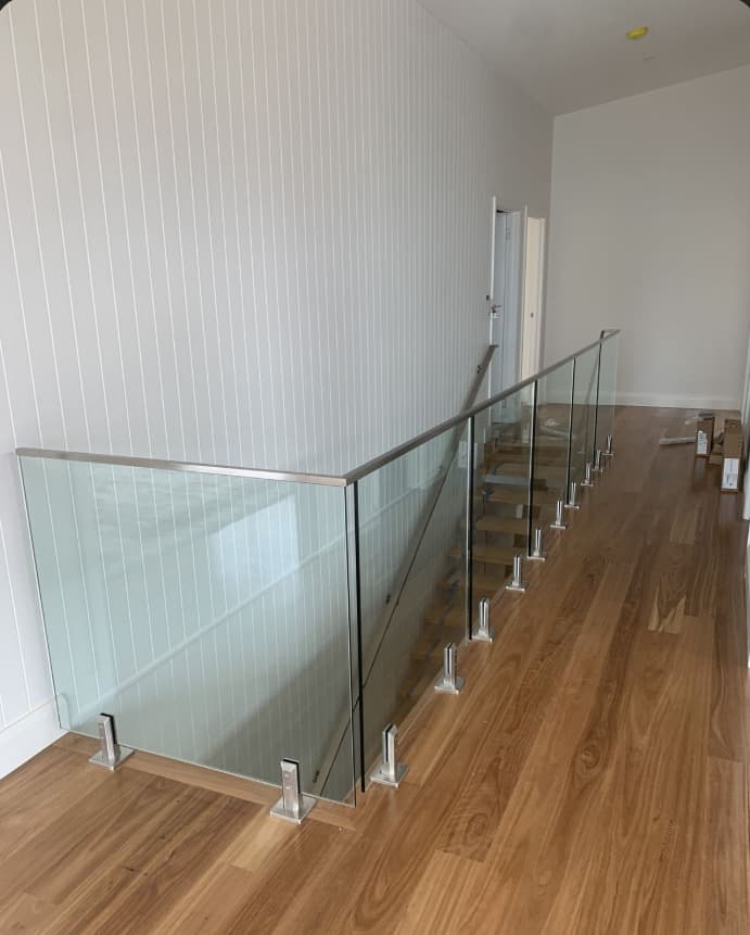 Frameless glass balustrade with stainless steel spigots on a wooden staircase