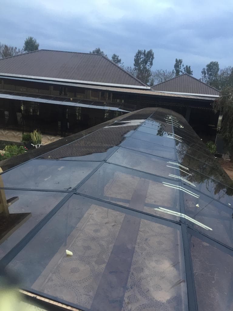 Structural glass canopy with aluminum framing over a tiled terrace